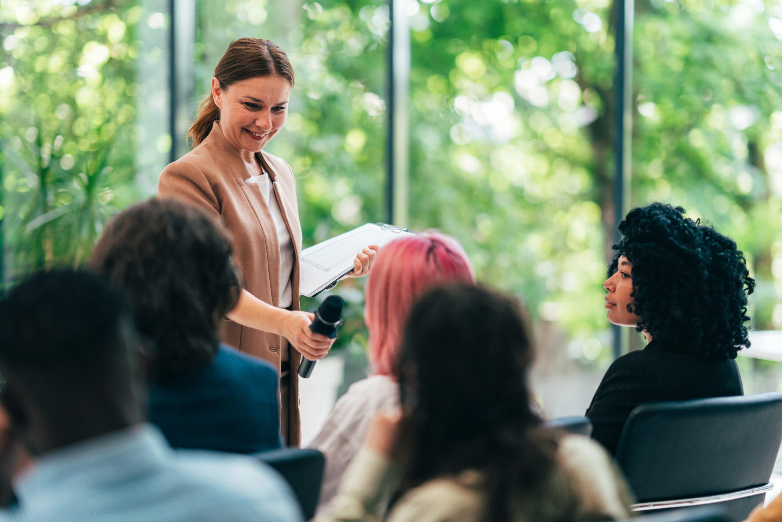 Business individuals at a short meet up. A lady is handing a mic to one of the attendee to answer a question.